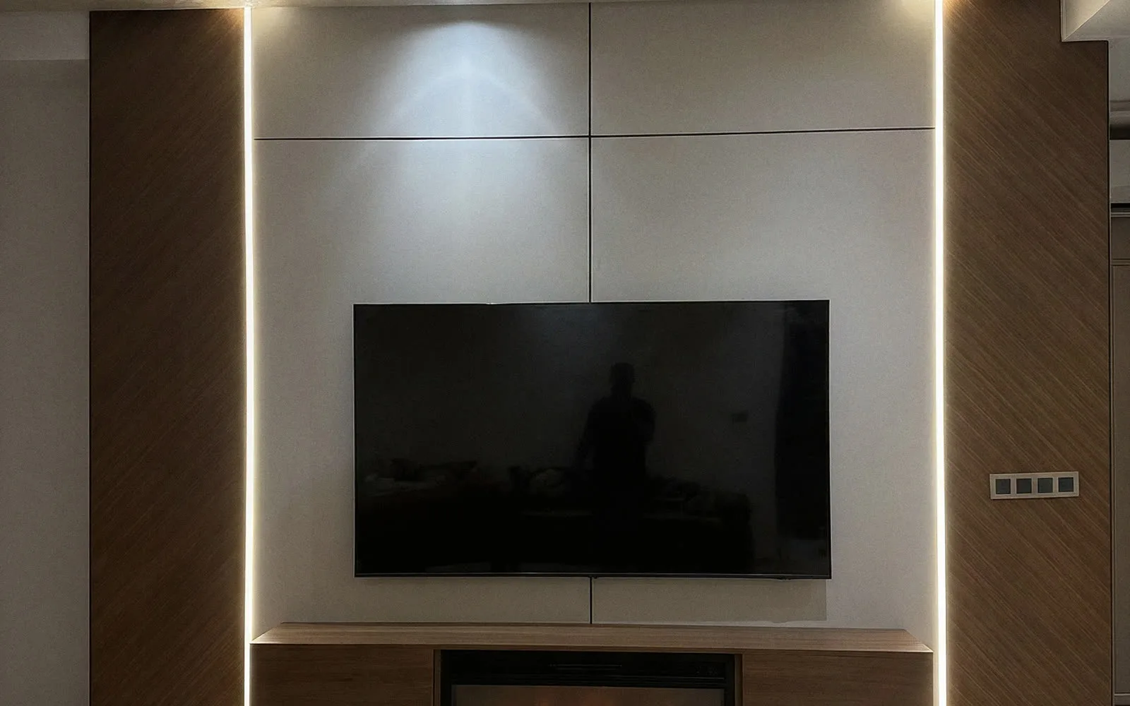 Mur TV fini en badil chipboard : panneaux laqués blancs, bandes bois verticales et éclairage LED intégré